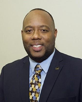 Dr. Kareem L Thompson smiling in a suit